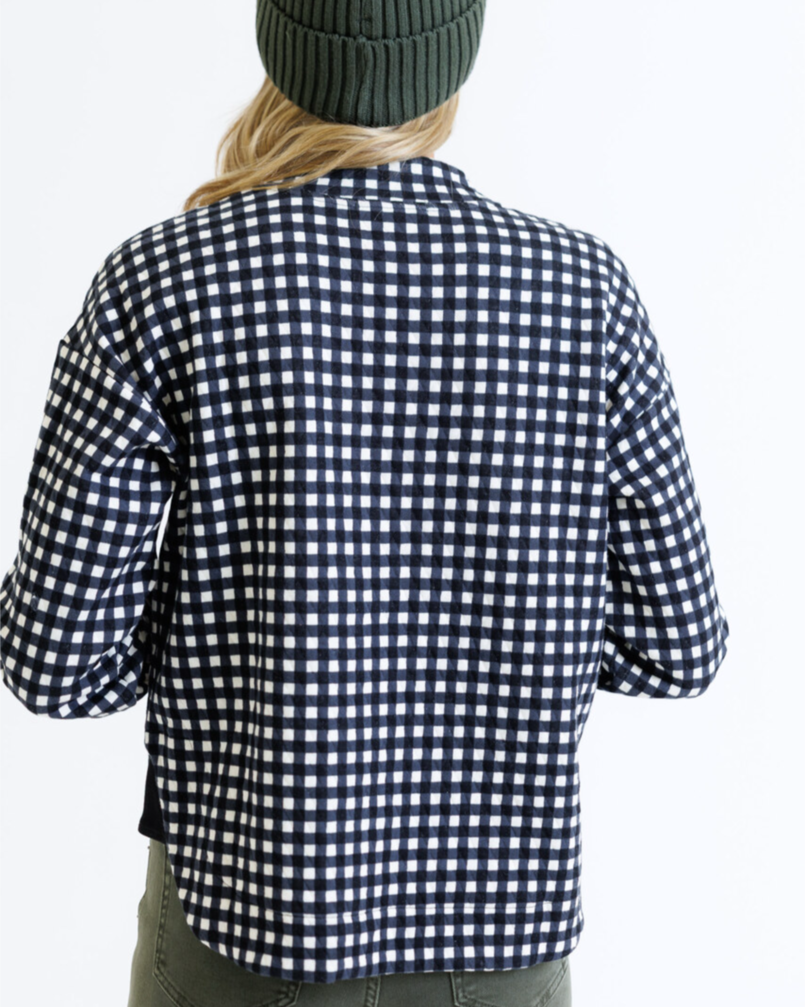 Person wearing a black and white checkered shirt with a plain background