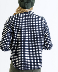 Person wearing a black and white checkered shirt with a plain background