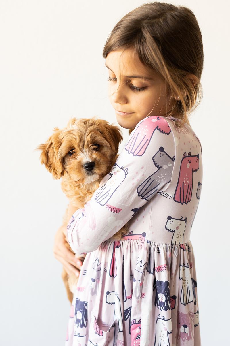 Girl in a patterned dress holding a small dog on a white background