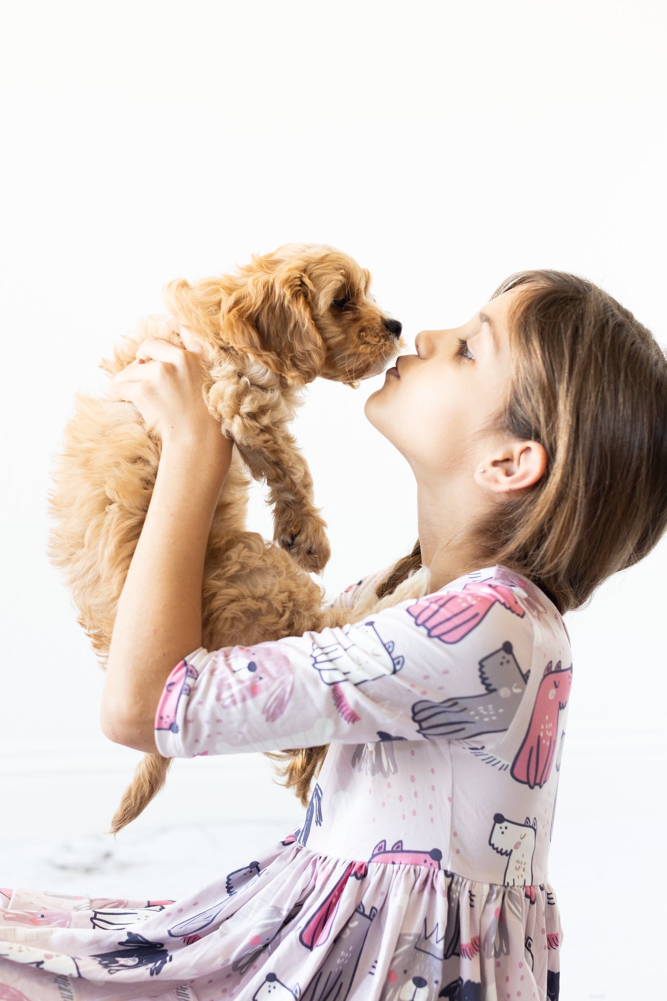 Young girl holding a small brown dog against a white background