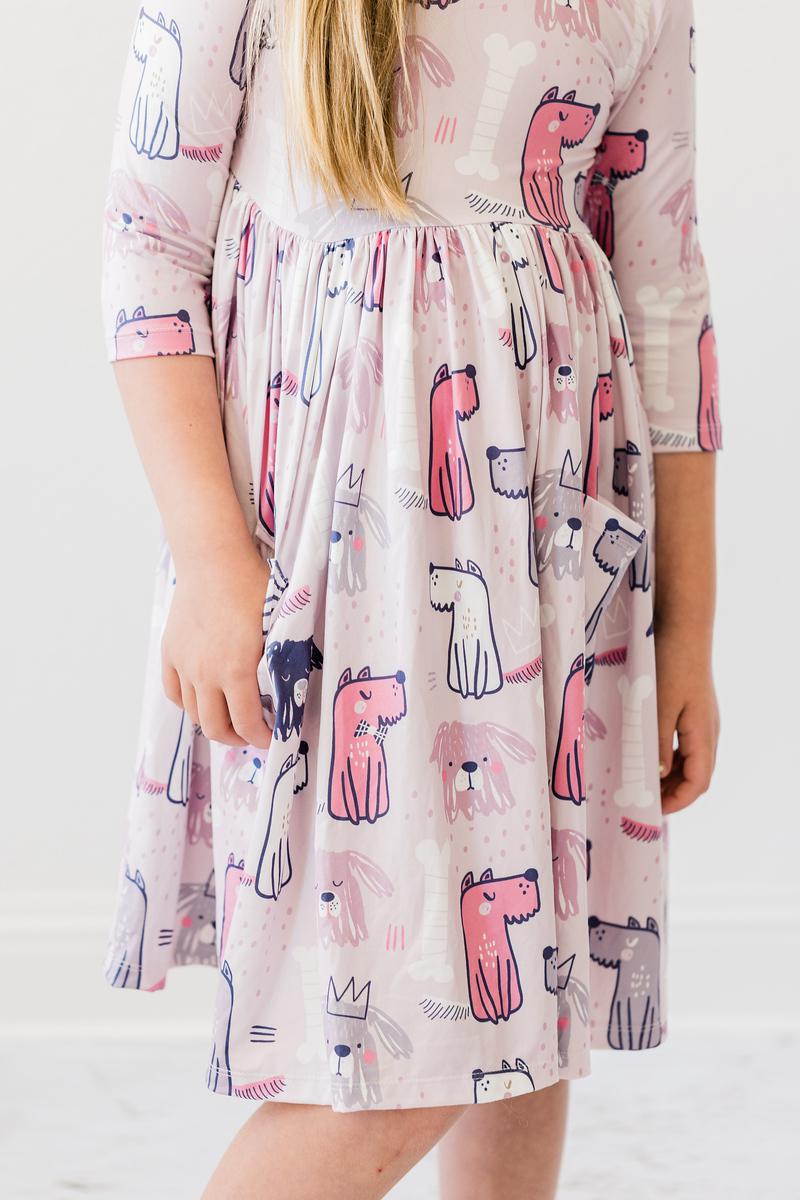 Person wearing a dress with pink dog illustrations on a white background