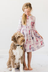 Girl in a patterned dress standing next to a dog on a white background