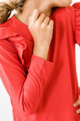 Person wearing a red long-sleeve shirt with a blurred background