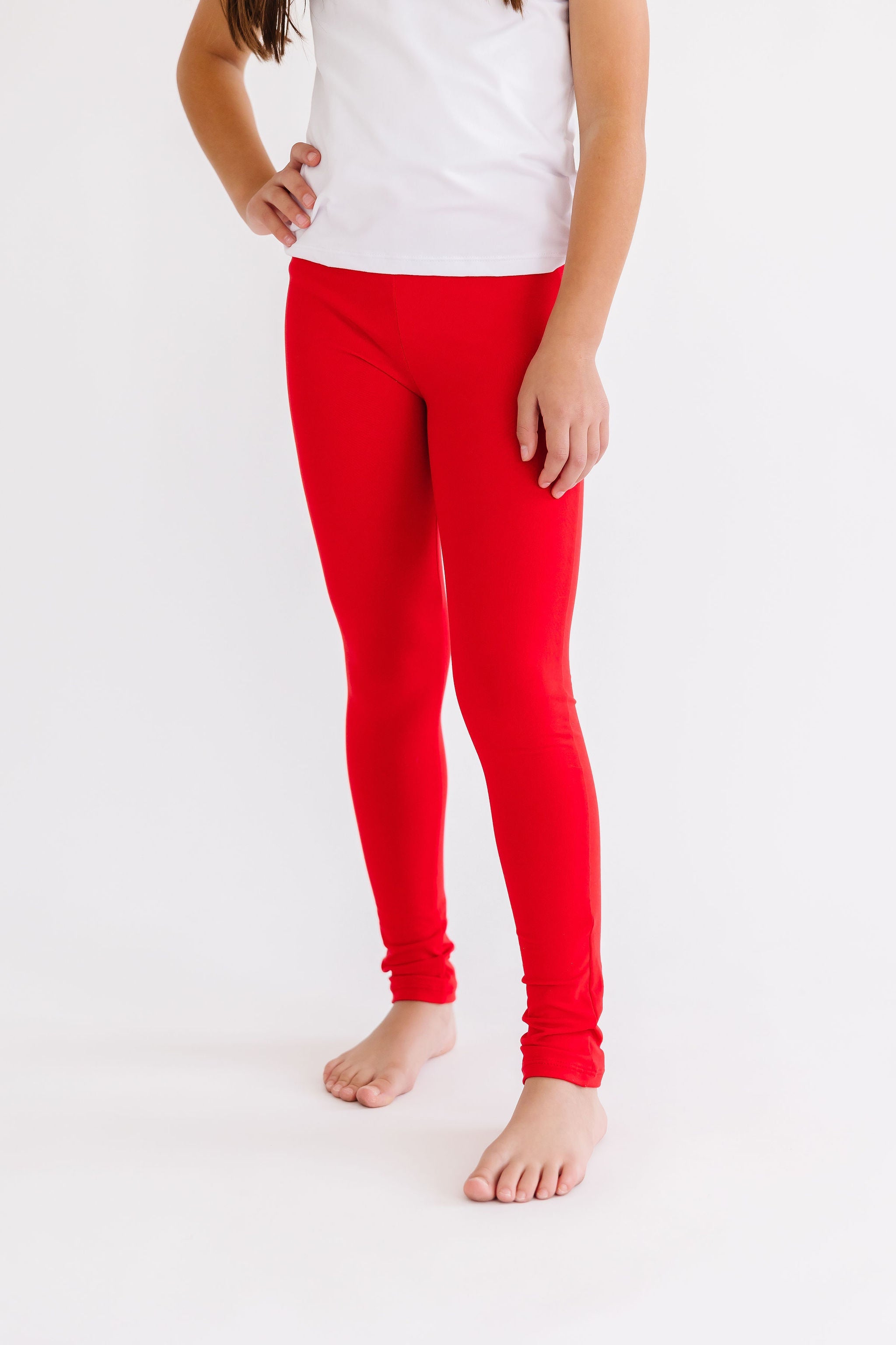 Person wearing red leggings and a white top on a light gray background