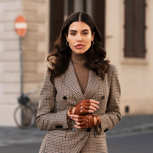 Woman wearing a checkered coat and brown gloves standing on a street.