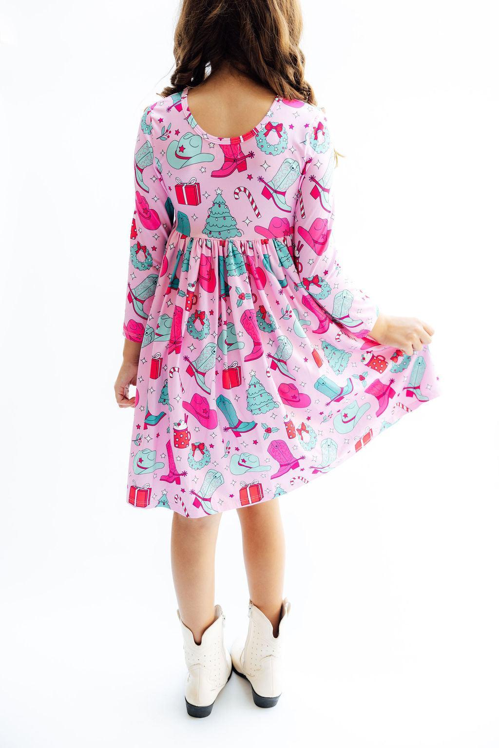 Child wearing a pink dress with colorful patterns on a white background