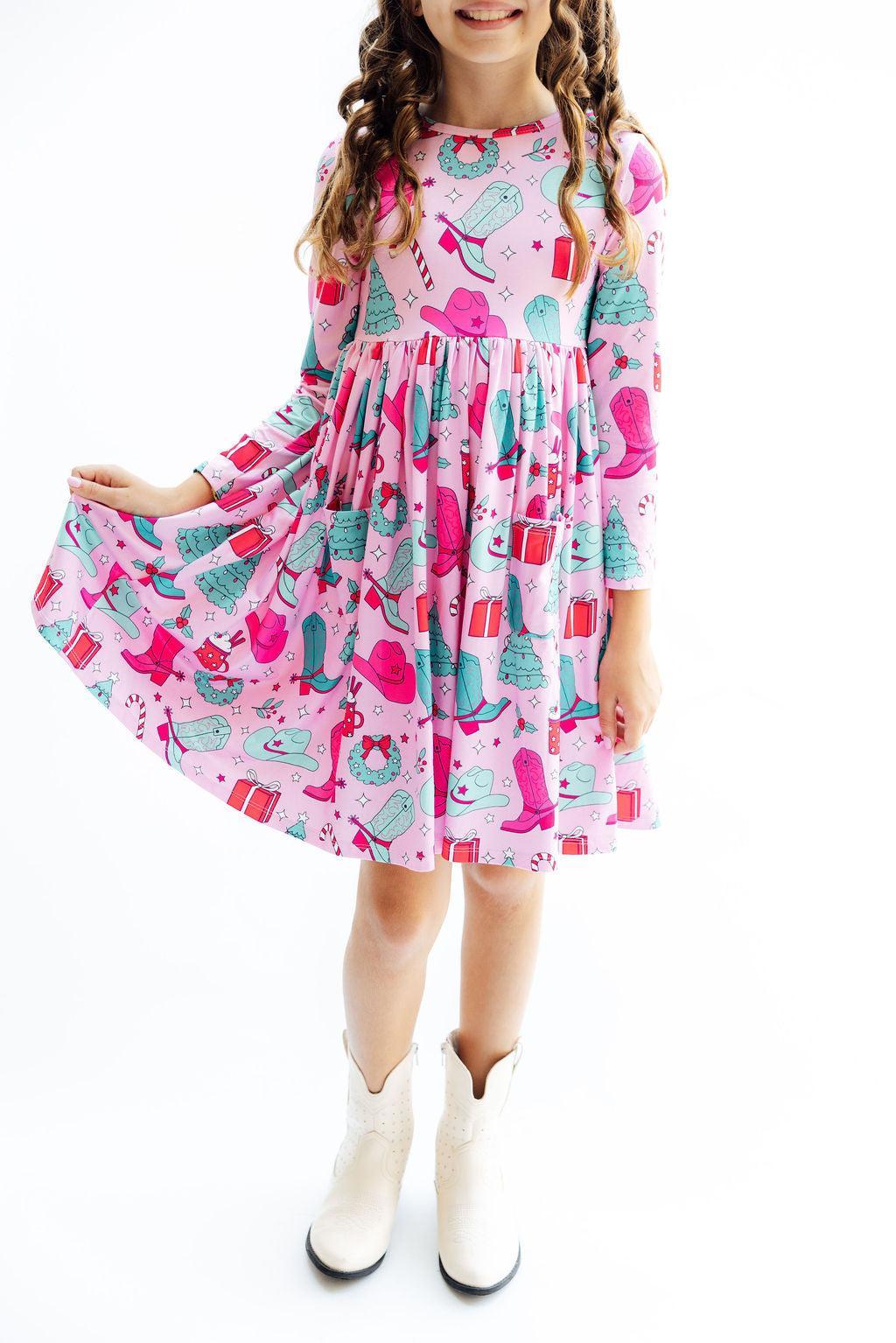 Young girl wearing a colorful dress with a pattern of shoes and boots on a white background