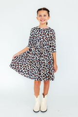 Young girl wearing a leopard print dress on a white background