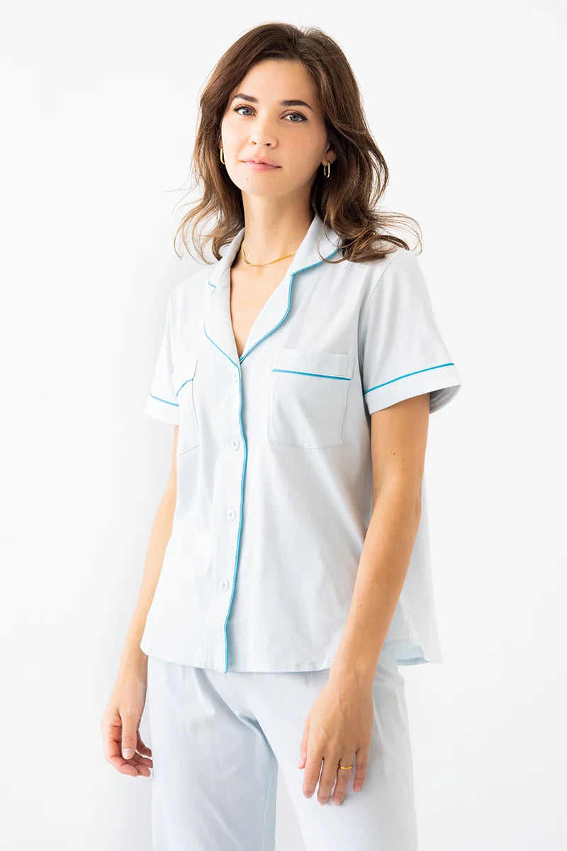 Woman wearing a white outfit with blue accents on a white background