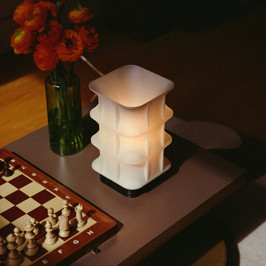 Decorative lamp on a table with a chessboard and vase of flowers