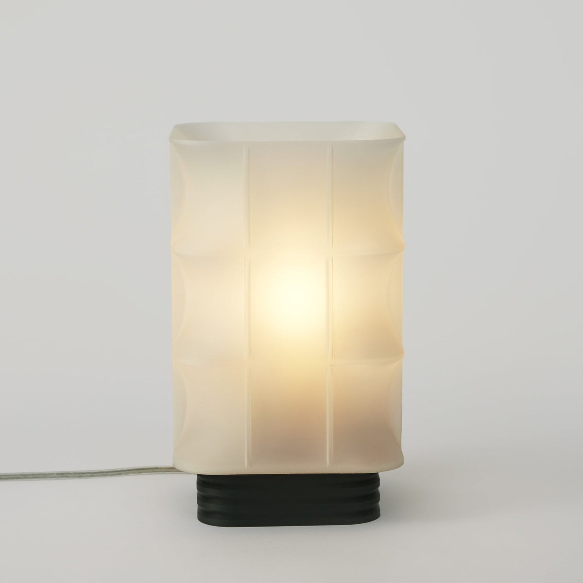 Table lamp with a white glass shade and black base on a light gray background