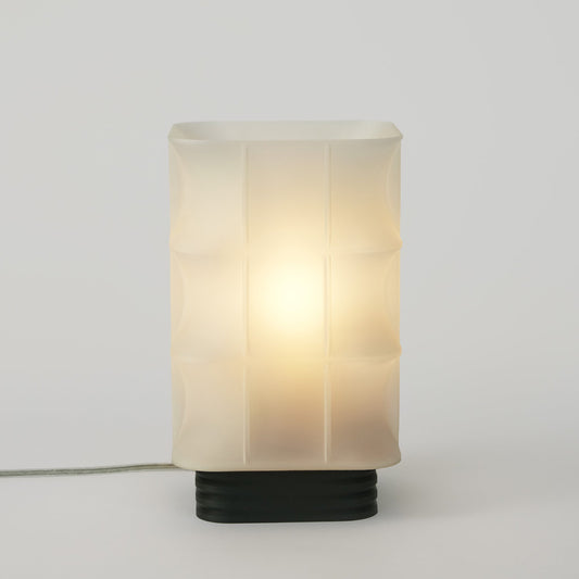 Table lamp with a white glass shade and black base on a light gray background