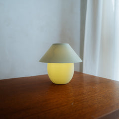 Small yellow lamp with a green shade on a wooden surface