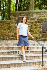 Woman walking up stone steps outdoors with greenery in the background