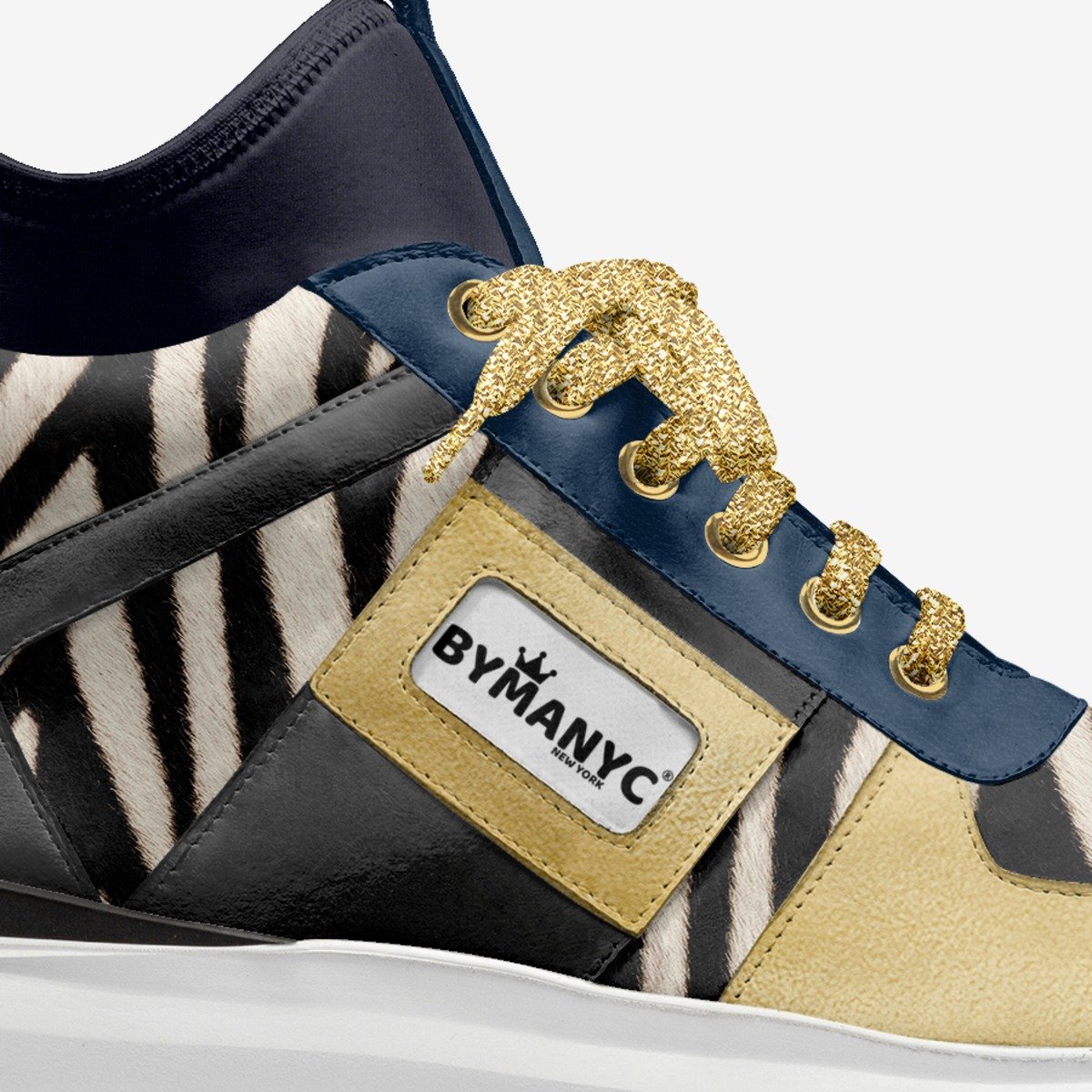 Close-up of a sneaker with zebra pattern, gold accents, and BYMANYC label.