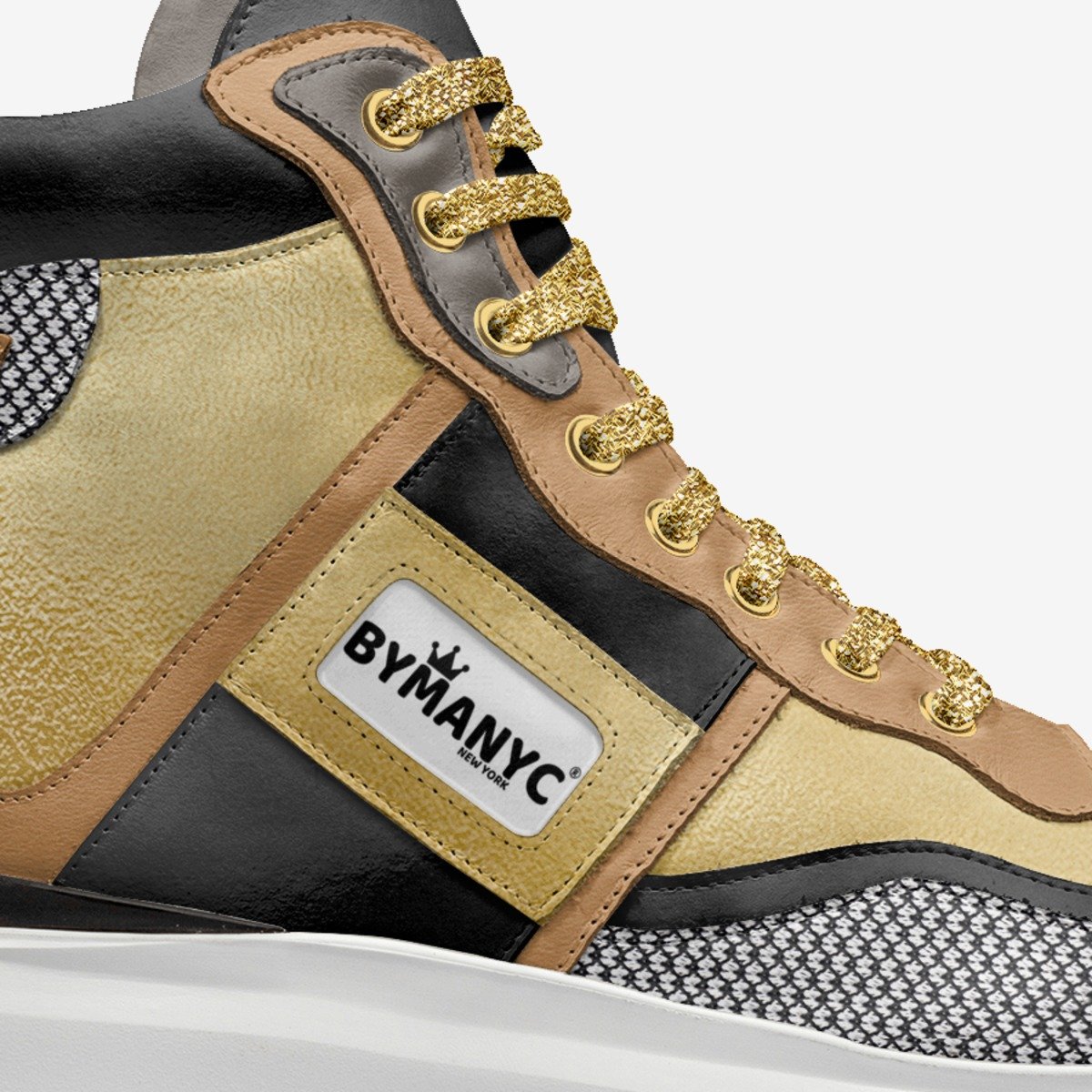 Close-up of a sneaker with gold laces and 'BYMANYC' label on a white background