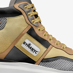 Close-up of a sneaker with gold laces and 'BYMANYC' label on a white background