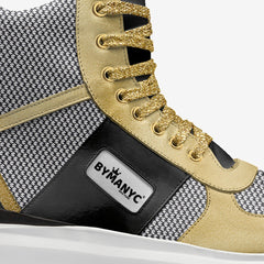 Close-up of a sneaker with gold laces and BYMANYC branding on a white background