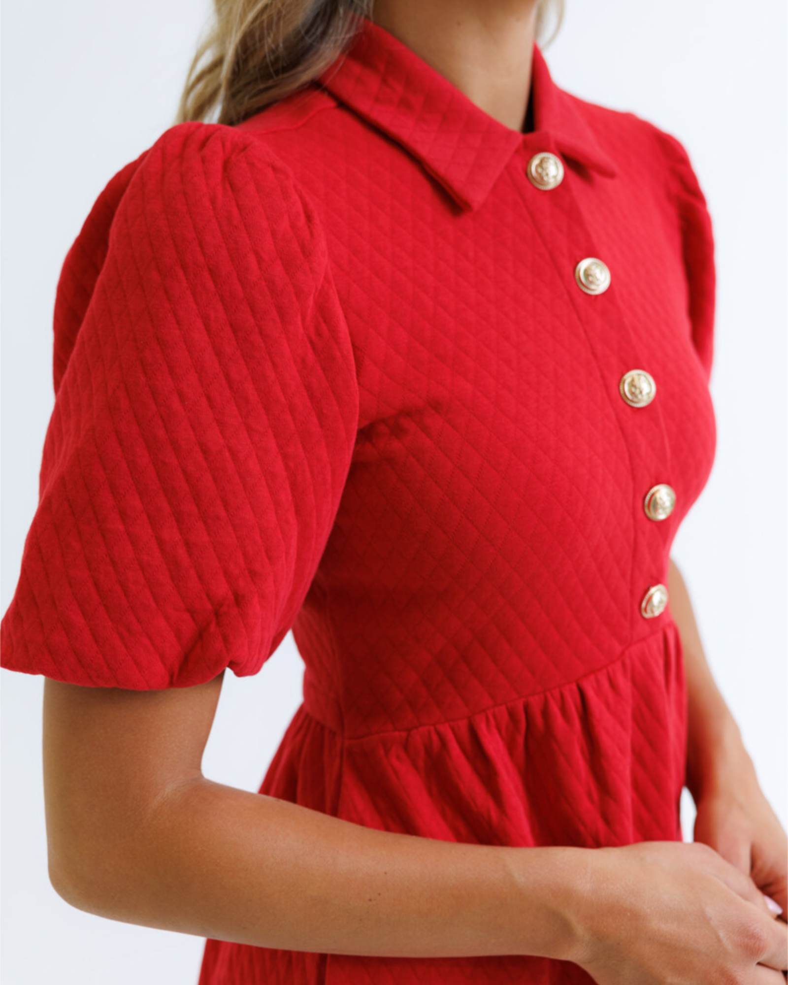 Red dress with puff sleeves and gold buttons on a white background