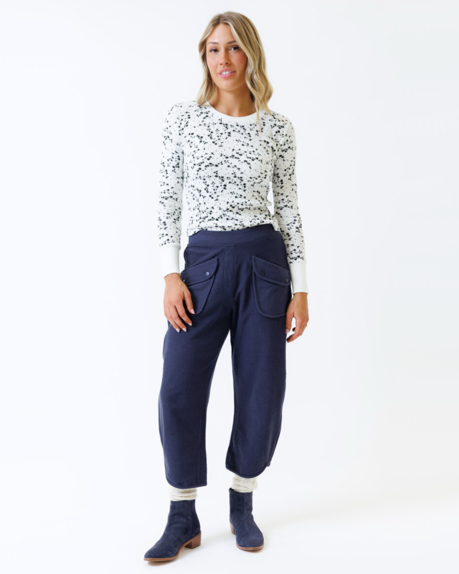 Woman wearing a patterned top and navy pants on a white background