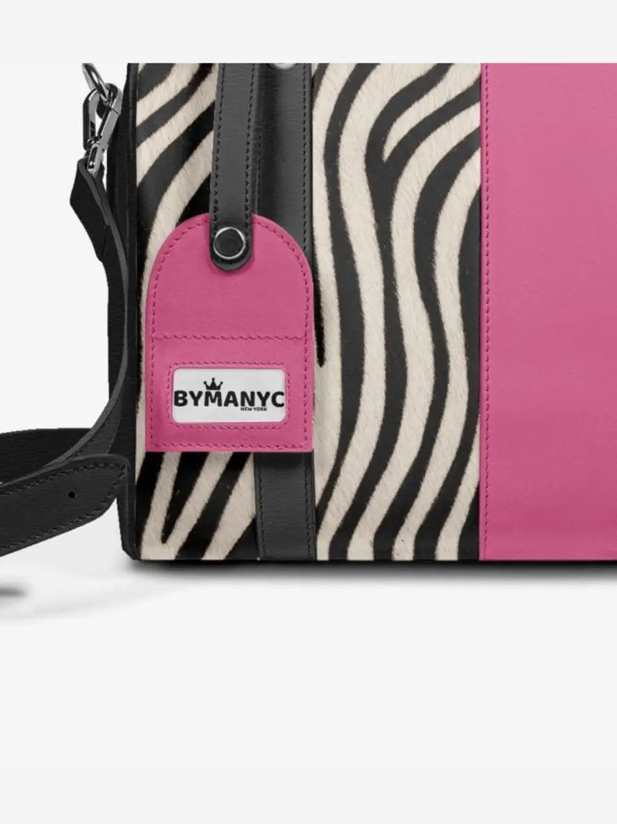 Handbag with zebra pattern and pink accent, featuring a BYMANYC tag.