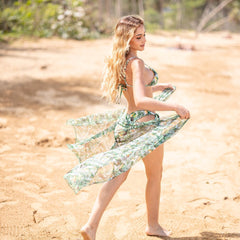 Woman in a floral dress standing on a sandy beach