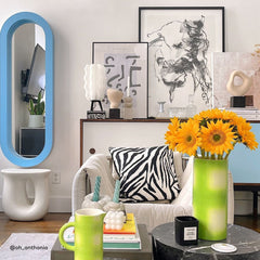 Modern living room with a zebra-patterned pillow, colorful decor, and a vase with yellow flowers.