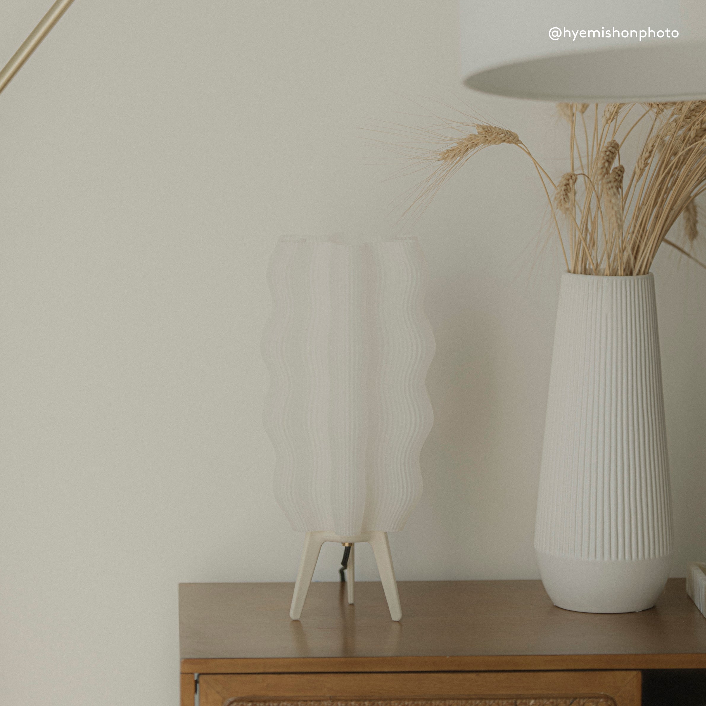 White textured lamp and vase on a wooden surface with a neutral background