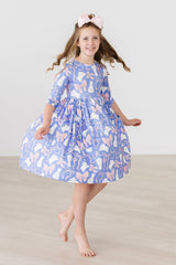 Young girl wearing a blue dress with pink floral pattern on a plain background
