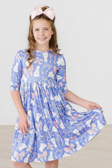 Young girl wearing a blue dress with cat and bow pattern on a white background