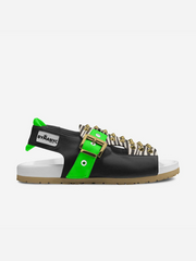 Black sandal with green strap and gold buckle on a white background