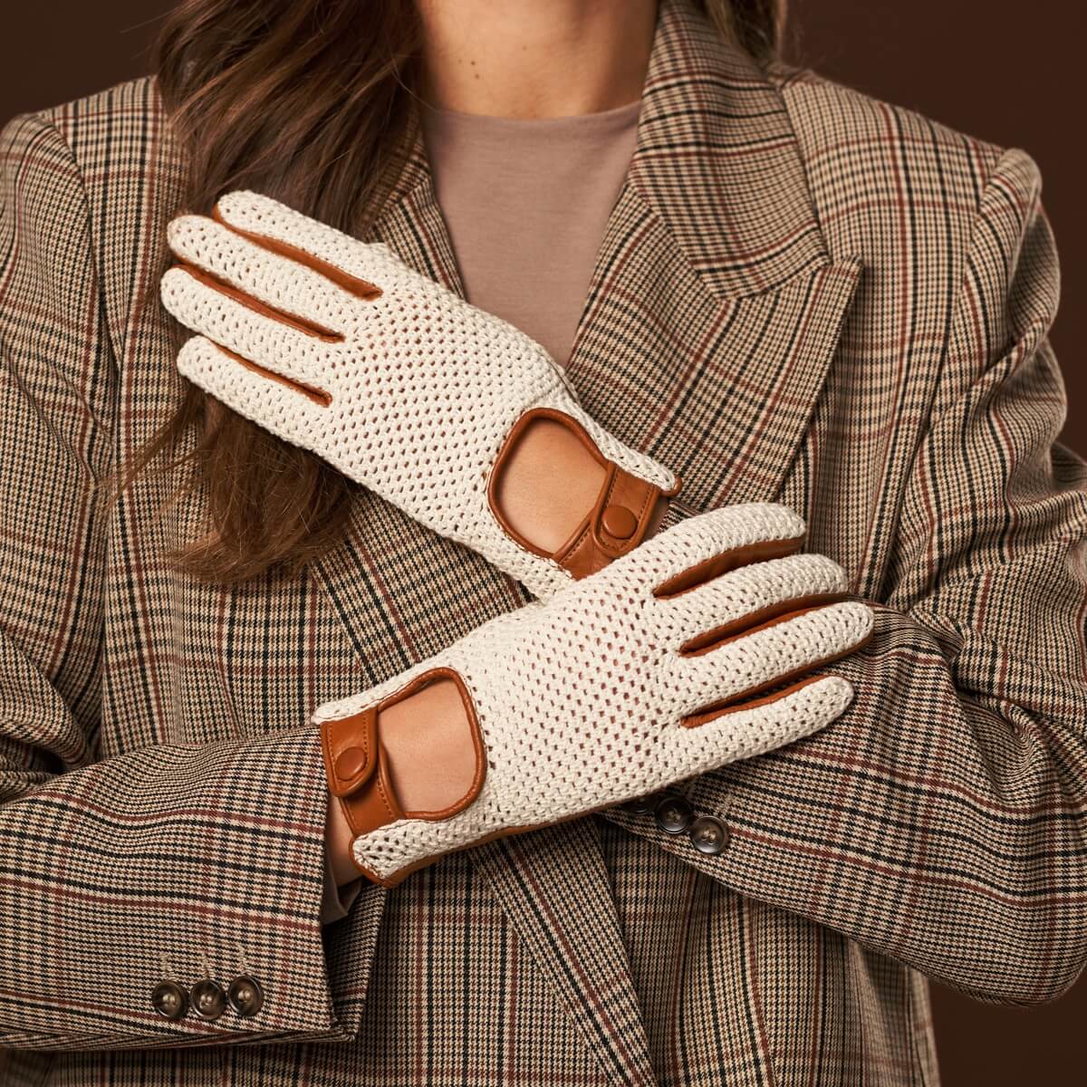 Person wearing cream gloves with brown accents and a plaid coat.