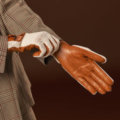 Brown leather glove with white lining held by a person wearing a plaid coat on a dark background
