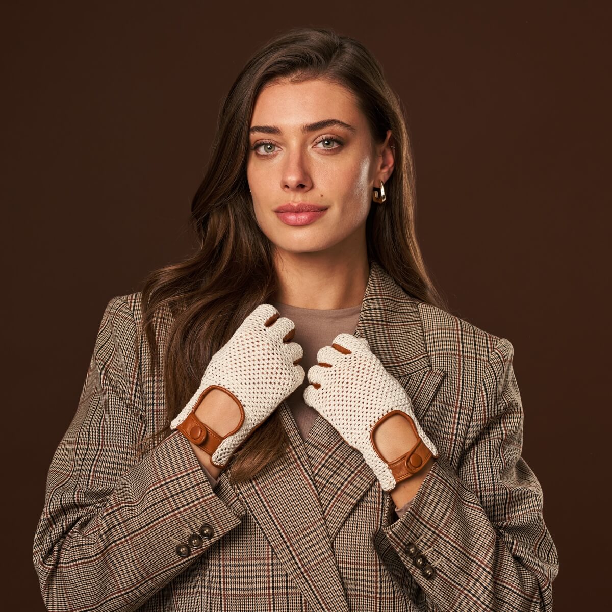Woman wearing a plaid coat and white gloves with brown accents on a brown background