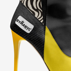 Yellow high-heeled shoe with black and zebra patterned heel, featuring BYMANYC logo.