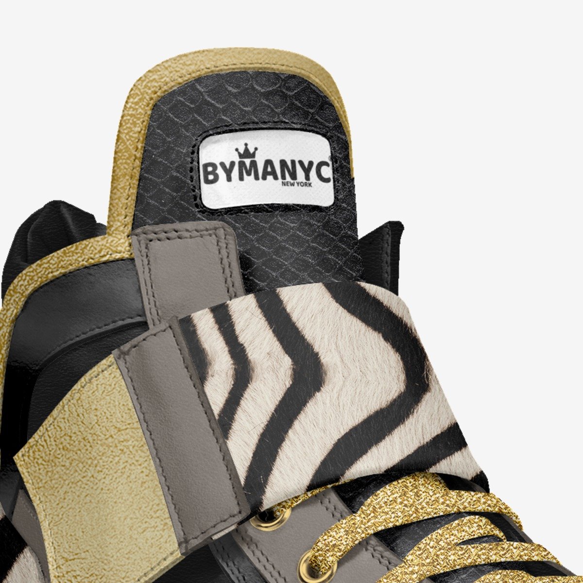 Close-up of a sneaker with zebra pattern and gold accents, featuring the BYMANYC New York logo.