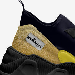 Black and yellow sneaker with 'BY MANYC' label on a white background