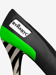Close-up of a shoe with green sole and Bymany brand label on a white background