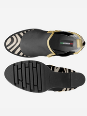 Black and gold shoe with zebra pattern sole on a white background