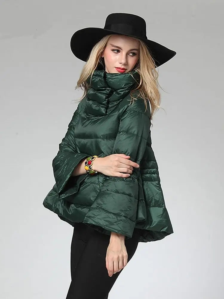 Woman wearing a green puffer jacket and black hat on a gray background