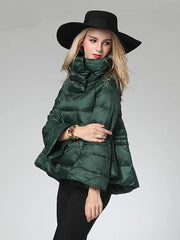 Woman wearing a green puffer jacket and black hat on a gray background