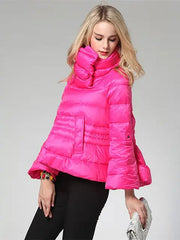 Woman wearing a bright pink puffer jacket on a gray background