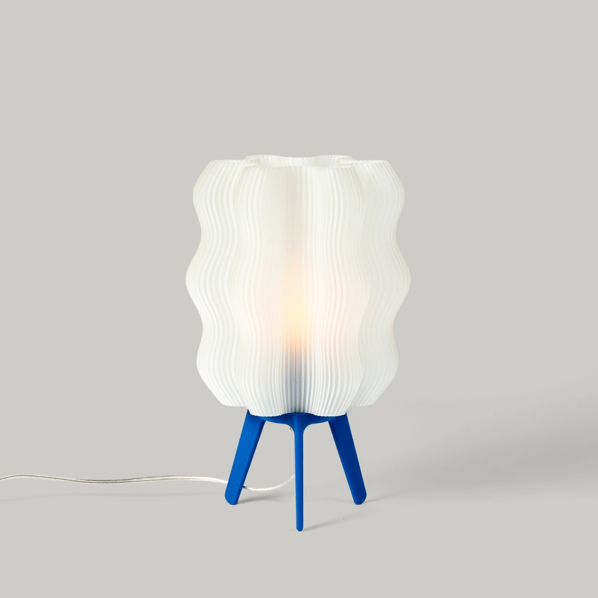 Table lamp with a white ribbed shade and blue base on a gray background