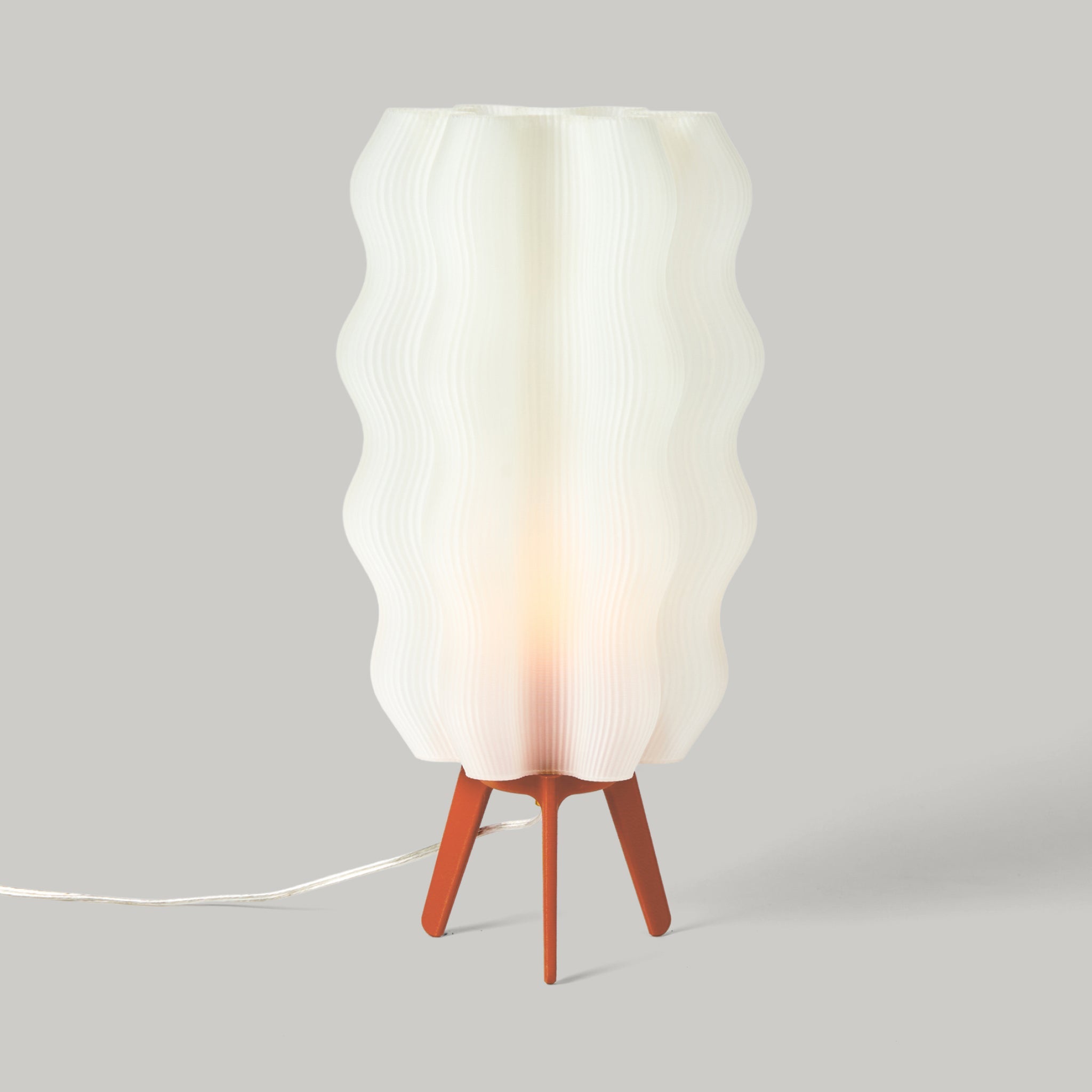 Table lamp with a white wavy shade and wooden base on a gray background