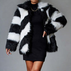 Person wearing a black and white striped fur coat over a black dress on a gray background