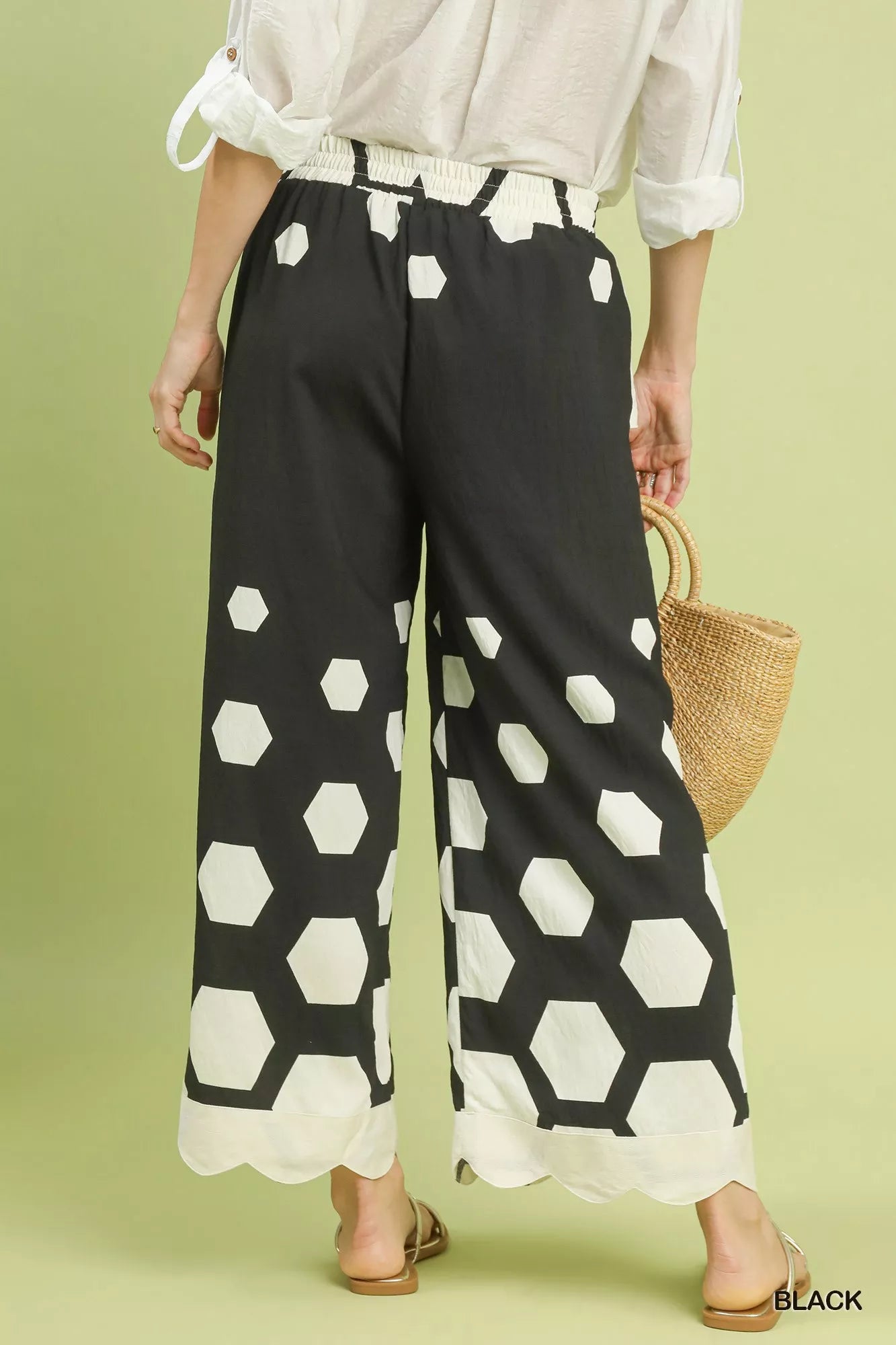 Person wearing black pants with white geometric pattern on a green background
