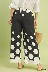 Person wearing black pants with white geometric pattern on a green background