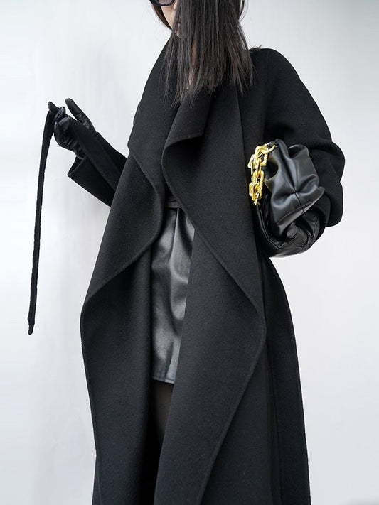 Person wearing a long black coat with a white background