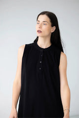 Woman wearing a black sleeveless top against a plain background