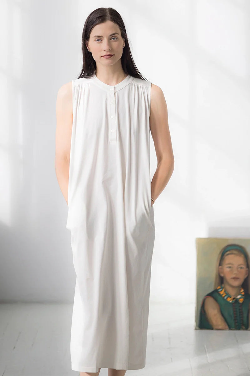 Woman wearing a white sleeveless dress against a plain background